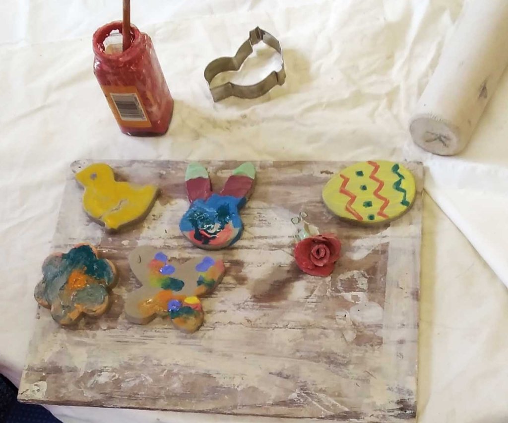 A selection of brightly coloured decorations on a table, alongside materials for creating and decorating ceramics
